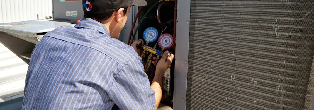 HVAC technician servicing a condenser unit in Northfield